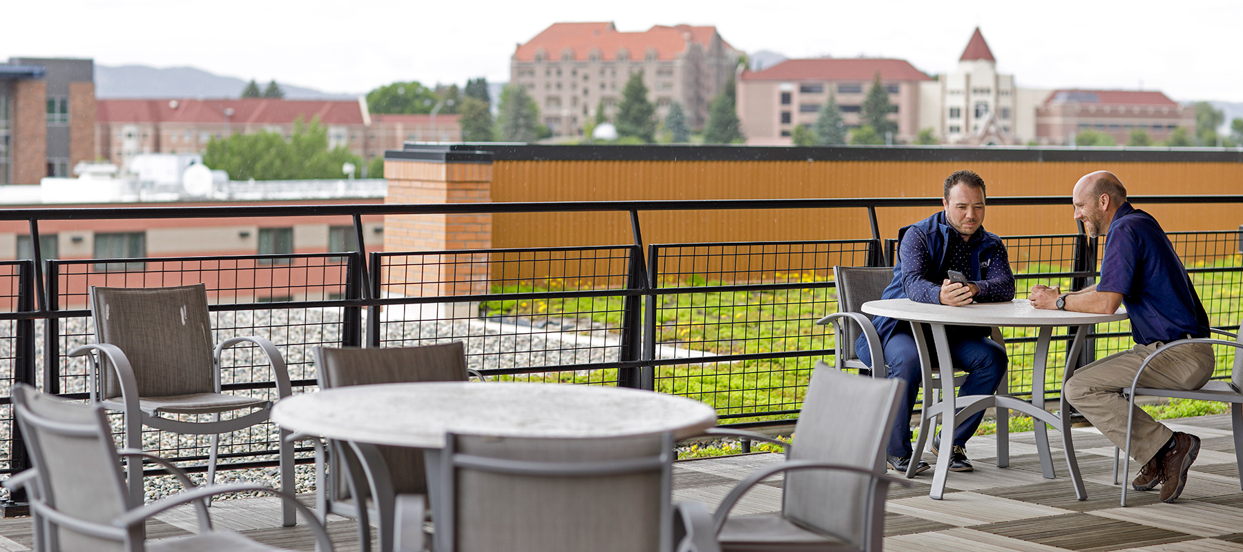 Two employees sitting at picnic tables on MSF's rooftop terace overlooking Helena, Montana.